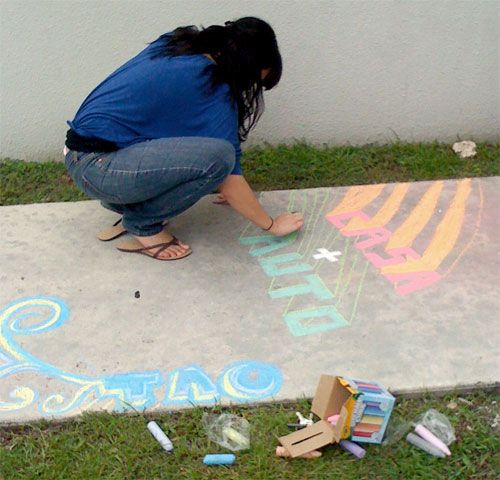 Woman drawing with chalk on a sidewalk