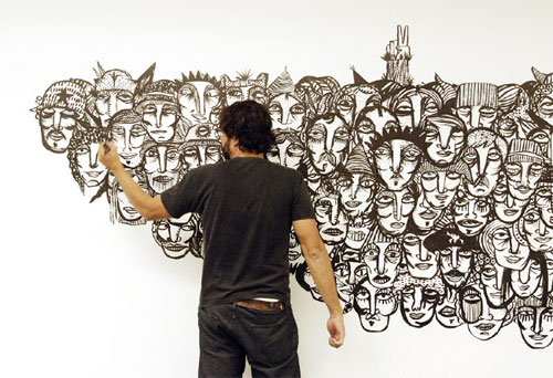 Artist drawing faces on a wall