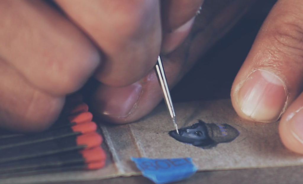 Close up photo of artist painting a tiny portrait of a man